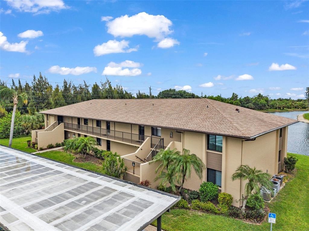 An exterior view of a two-story apartment building with tan stucco walls and a shingled roof — 4000 OAKVIEW DRIVE UNIT L4, PORT CHARLOTTE, FL