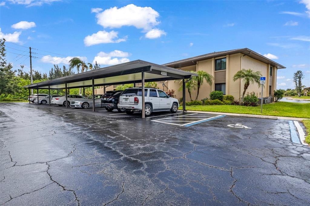 A covered parking structure sits in front of a two-story apartment building under a blue sky — 4000 OAKVIEW DRIVE UNIT L4, PORT CHARLOTTE, FL