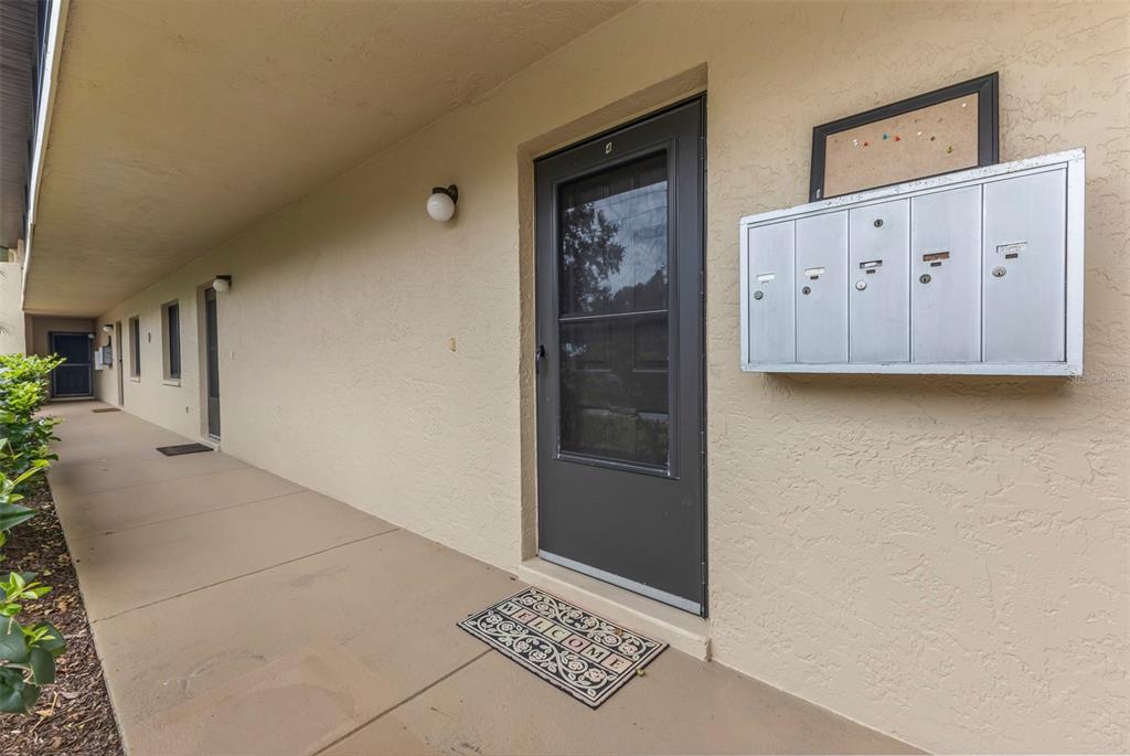 An exterior walkway features a row of apartment doors, a welcome mat, and wall-mounted mailboxes — 4000 OAKVIEW DRIVE UNIT L4, PORT CHARLOTTE, FL
