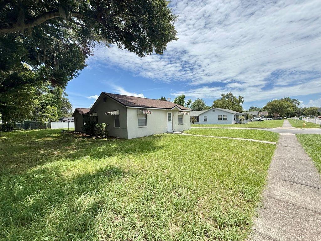 A single-story house with a light-colored exterior and a brown roof sits on a lawn — 123 PENNSYLVANIA AVENUE, WINTER GARDEN, FL