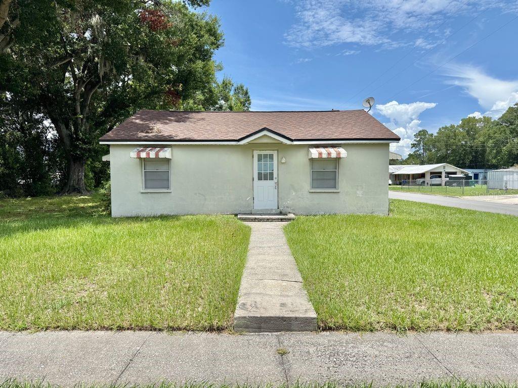 A single-story house with a light green exterior, a brown roof, and a front walkway — 123 PENNSYLVANIA AVENUE, WINTER GARDEN, FL