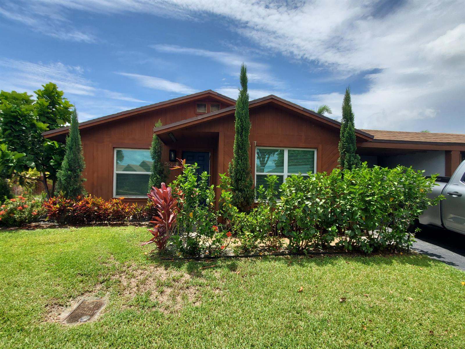A brown single-story house features a front lawn, landscaping, and a driveway with a vehicle — 558 SE 27th Terrace # 558, Boynton Beach FL 33435, BOYNTON BEACH, FL