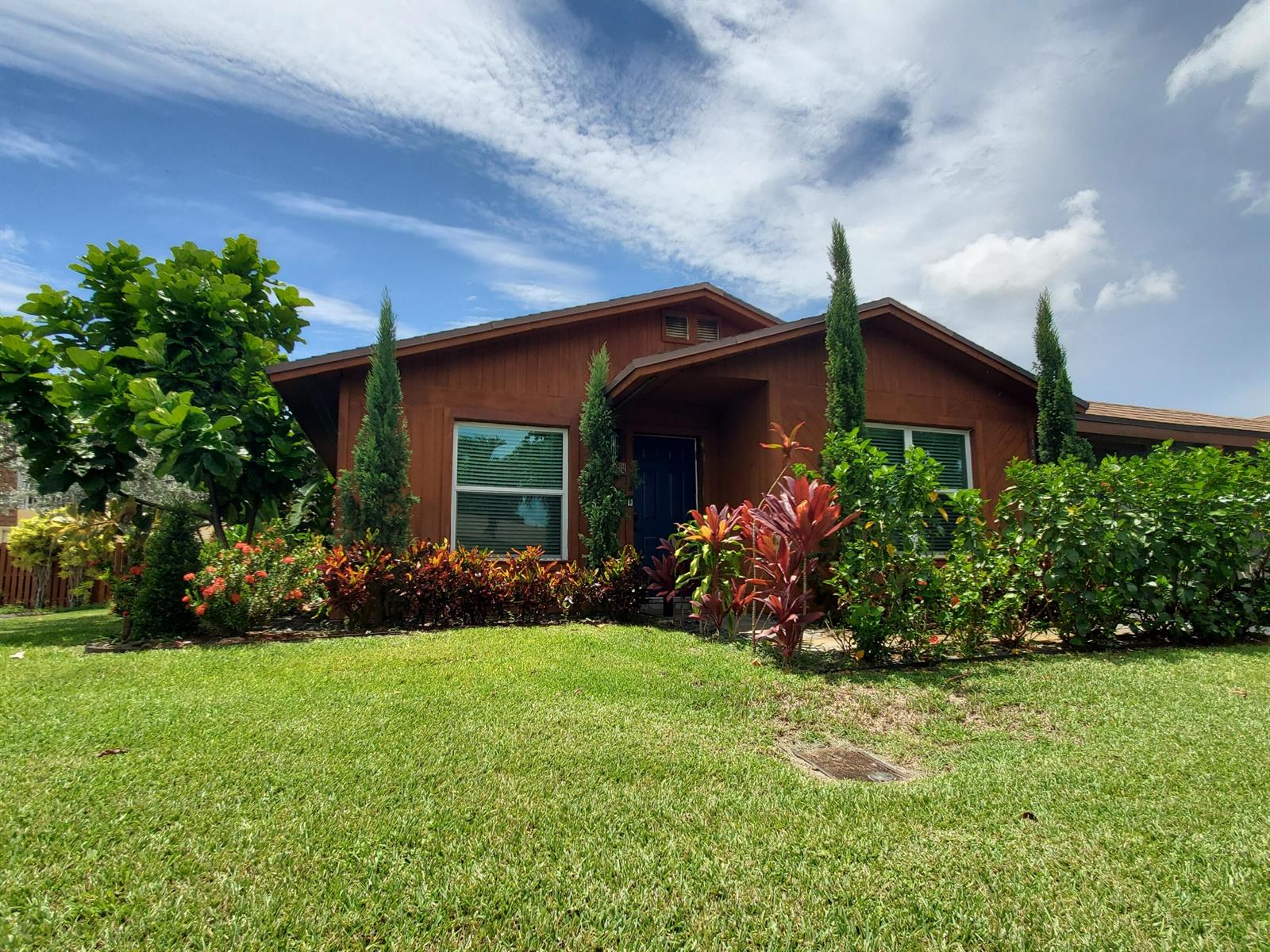 A brown house with a dark blue front door is surrounded by lush tropical landscaping — 558 SE 27th Terrace # 558, Boynton Beach FL 33435, BOYNTON BEACH, FL
