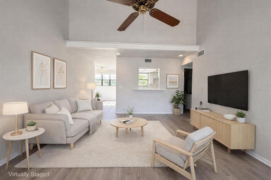 A living room with a vaulted ceiling, light wood flooring, and neutral-toned furniture — 516 42ND STREET COURT W, PALMETTO, FL
