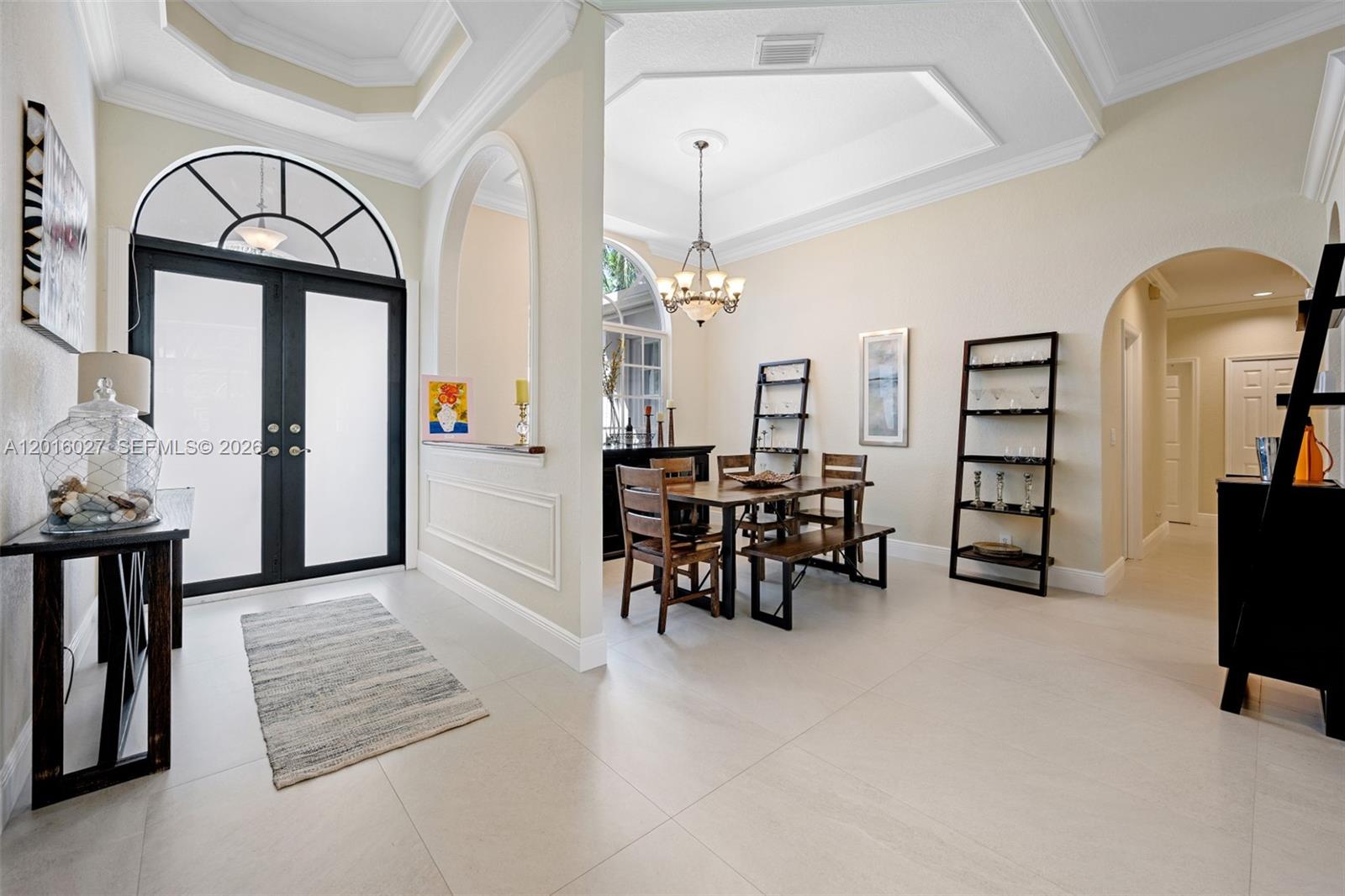 A dining room with a tray ceiling, wooden furniture, and an adjacent entryway with tile floors — 2538 Eagle Run Dr, Weston FL 33327, WESTON, FL