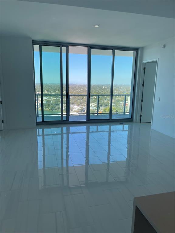 An empty room with white tile flooring and large sliding glass doors overlooking a landscape — 400 CENTRAL AVE UNIT 2708, ST PETERSBURG, FL