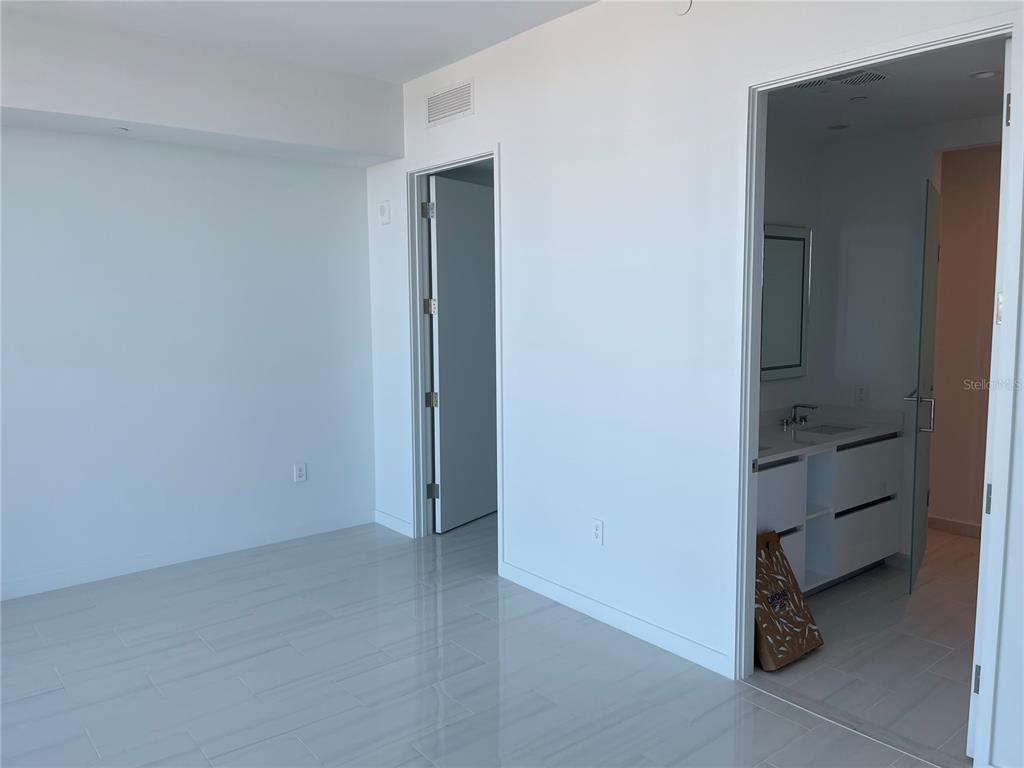 A room with light-colored tile flooring and two doorways leading to a bathroom and hallway — 400 CENTRAL AVE UNIT 2708, ST PETERSBURG, FL
