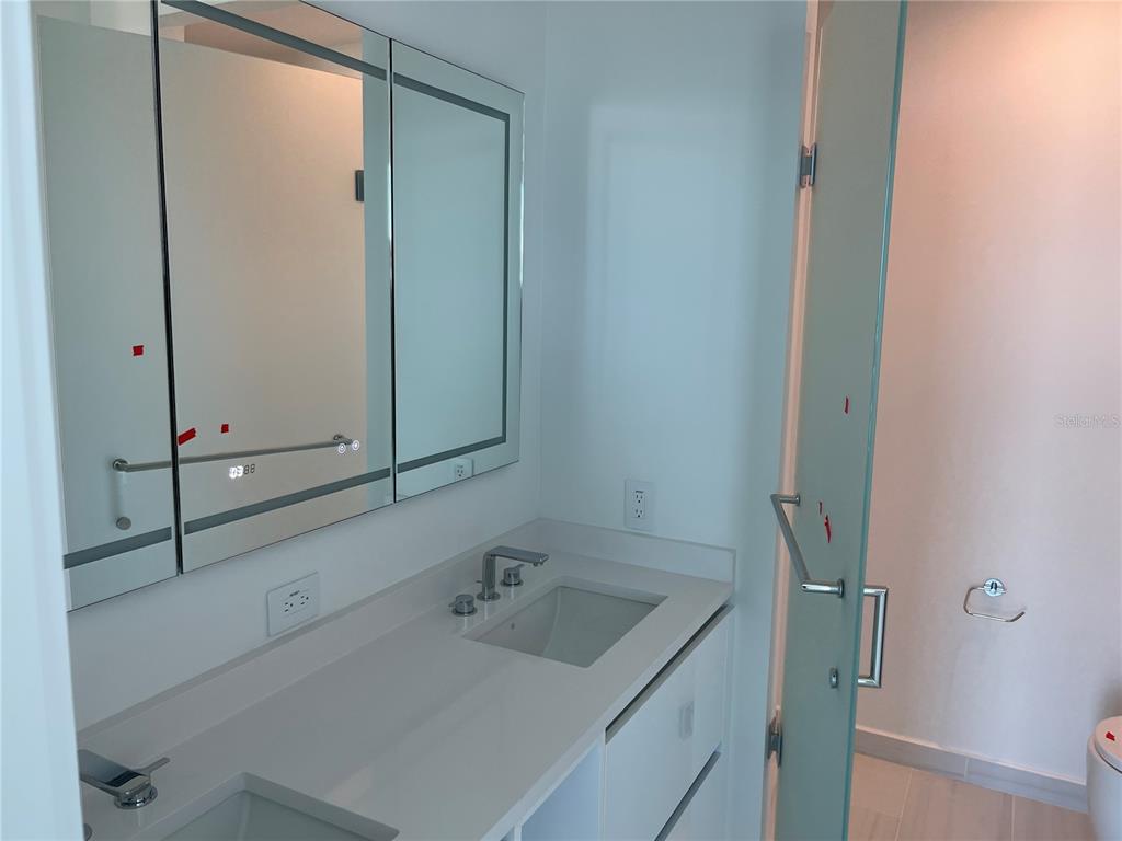 A modern bathroom features a white vanity, a triple-mirror cabinet, and a glass shower door — 400 CENTRAL AVE UNIT 2708, ST PETERSBURG, FL