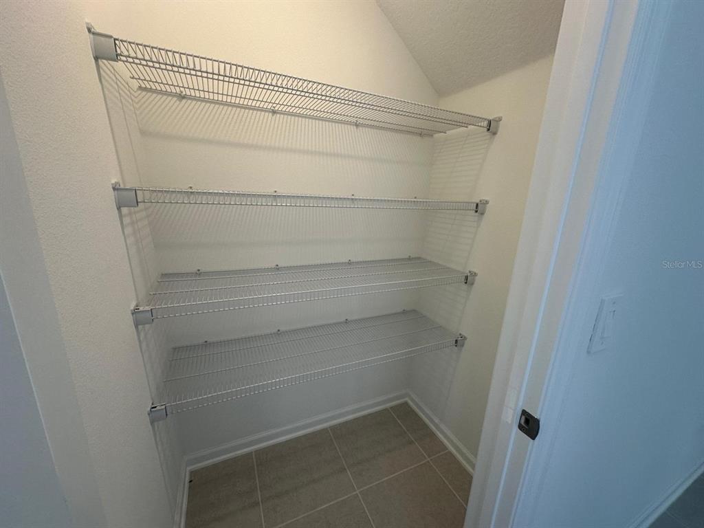 A walk-in pantry with white walls, tiled flooring, and four wire shelving units — 2895 TRANSFORMATION WAY, CLERMONT, FL