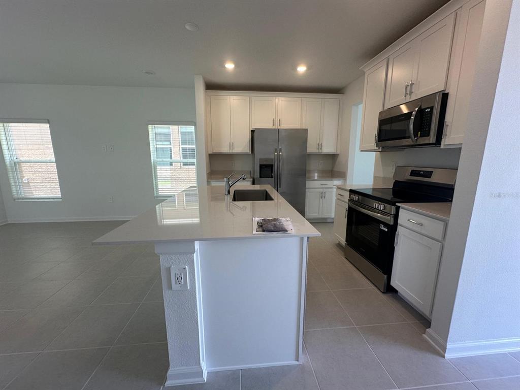 A kitchen with white cabinets, stainless steel appliances, and a quartz-topped island — 2895 TRANSFORMATION WAY, CLERMONT, FL