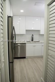 A modern kitchen features white cabinets, stainless steel appliances, and light wood-look flooring — 964 N 18th Ct, Hollywood FL 33020, HOLLYWOOD, FL