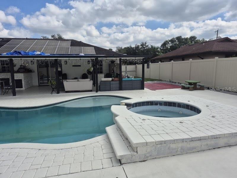 A backyard features a swimming pool, a raised hot tub, and a covered patio area — 8016 APACHE LANE, LAKELAND, FL