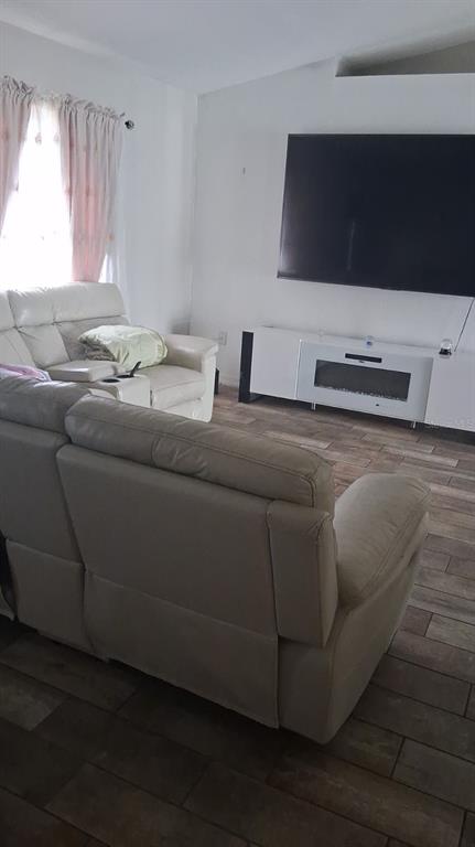 A living room features light-colored reclining sofas, a wall-mounted television, and a white media console — 8016 APACHE LANE, LAKELAND, FL