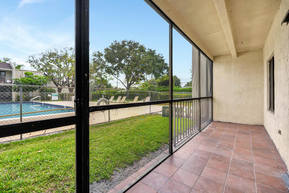A screened-in patio with tile flooring overlooks a fenced swimming pool and grassy area — 150 Pineview Road # F3, Jupiter FL 33469, JUPITER, FL