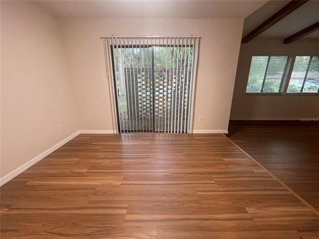 A room with wood-look flooring and sliding glass doors leading to a patio — 3810 NW 28TH TERRACE, GAINESVILLE, FL