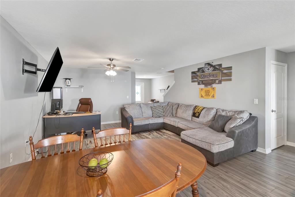 A living room with a sectional sofa, dining table, and desk area on wood-look flooring — 1691 WYNFORD CIRCLE, TAVARES, FL