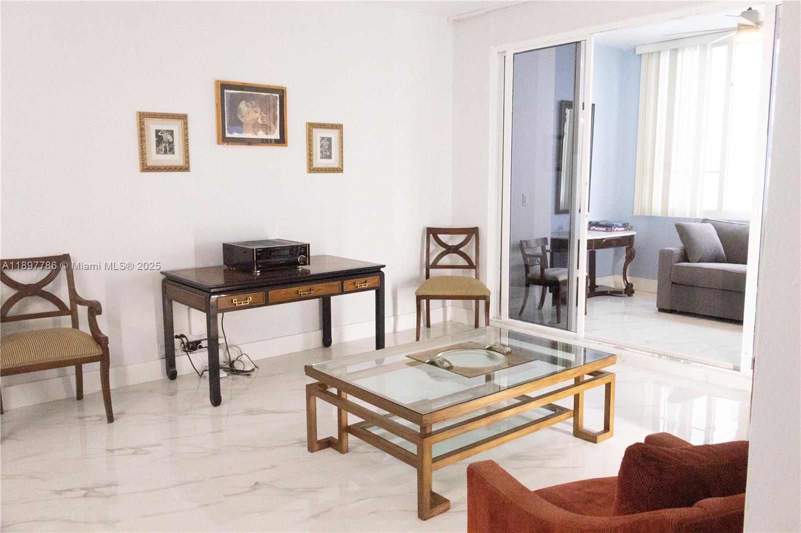 A living room features a glass coffee table, wooden desk, chairs, and marble flooring — 5005 Collins Ave # 1523, Miami Beach FL 33140, MIAMI BEACH, FL