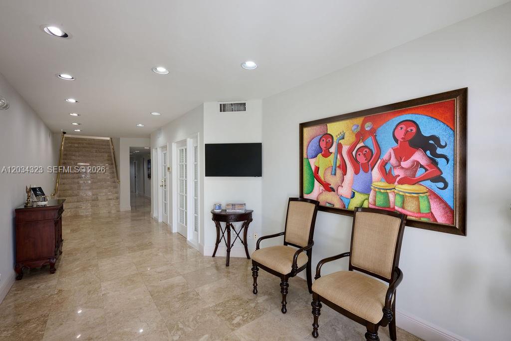 A hallway with marble floors, two chairs, a small table, and a large colorful painting — 355 Palermo Ave, Coral Gables FL 33134, CORAL GABLES, FL