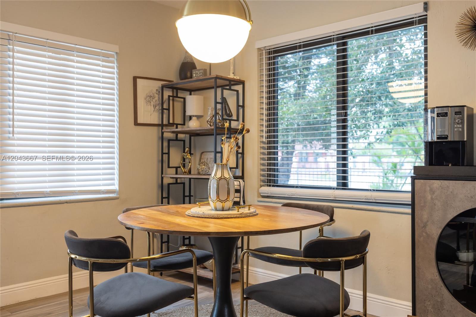A dining area features a round wooden table, four dark chairs, and a metal shelving unit — MIAMI, FL