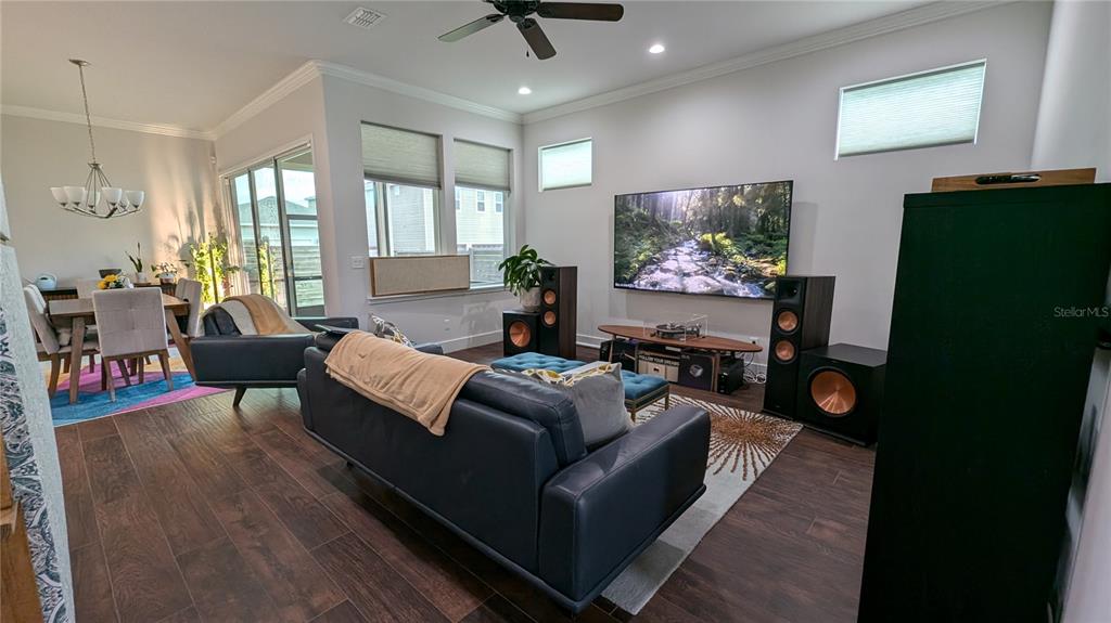 A living room features a large television, floor-standing speakers, a dark sofa, and wood flooring — 7476 SW 66TH LANE, GAINESVILLE, FL