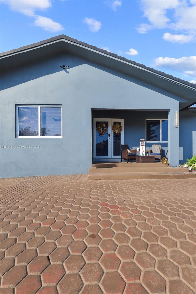 A blue house exterior features a double front door, a paved driveway, and a porch — 9795 NW 27th Ter, Doral FL 33172, DORAL, FL