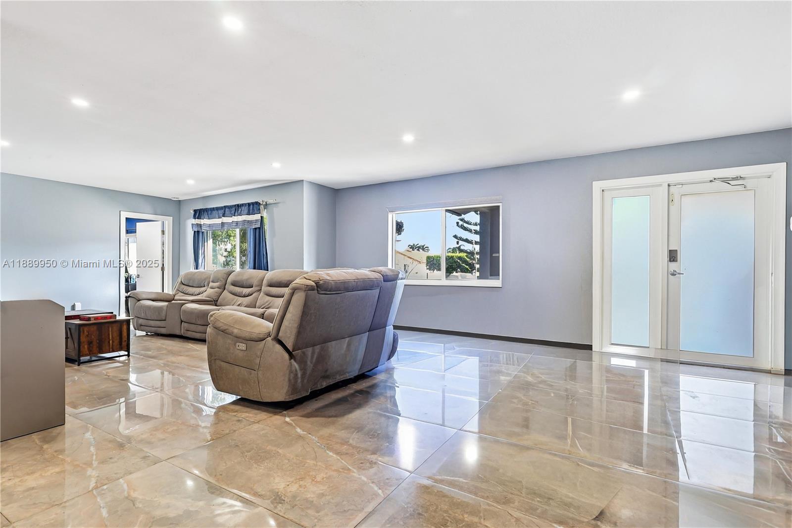 A living room features light blue walls, large glossy floor tiles, and a gray sectional sofa — 9795 NW 27th Ter, Doral FL 33172, DORAL, FL