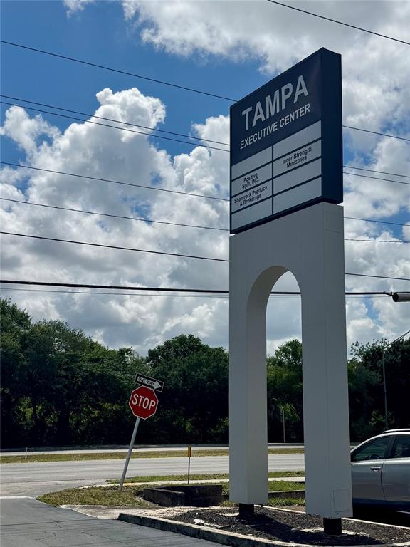 A tall, white, arched sign for the Tampa Executive Center stands near a stop sign — 5118 N 56TH STREET UNIT 123, TAMPA, FL