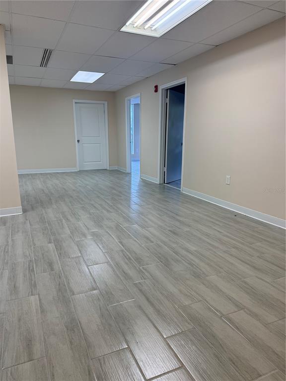 An empty office space with light-colored walls, wood-look tile flooring, and two open doorways — 5118 N 56TH STREET UNIT 123, TAMPA, FL