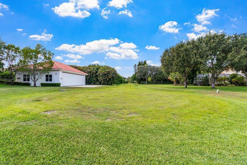 A large grassy yard features a detached garage with a red tile roof — 15465 Take Off Place, Wellington FL 33414, WELLINGTON, FL