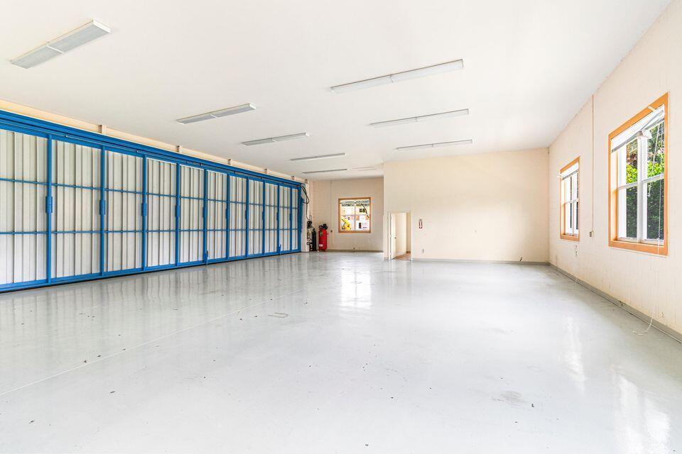 A large, empty garage with a polished concrete floor, blue sliding doors, and white walls — 15465 Take Off Place, Wellington FL 33414, WELLINGTON, FL