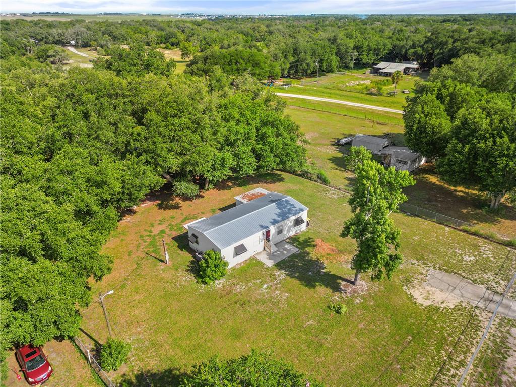 An aerial view shows a single-story house with a metal roof on a grassy lot — 6543 LURE COURT, LAKE WALES, FL