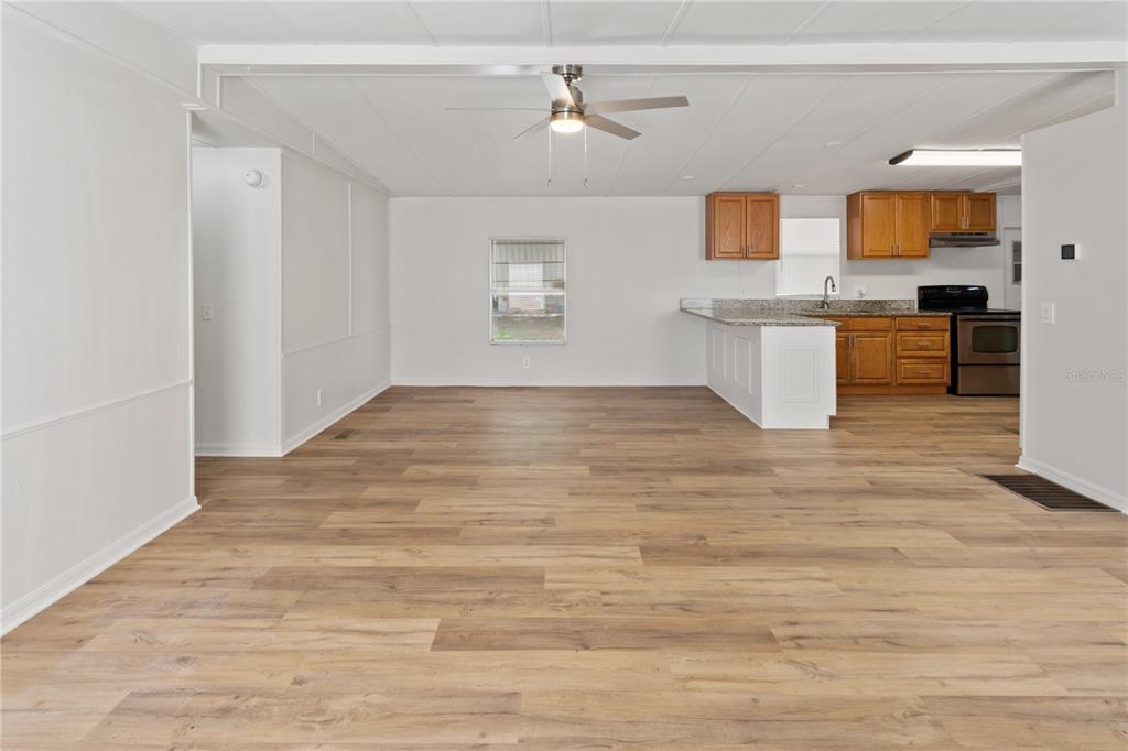 An open-concept living area features light wood-look flooring, white walls, and a kitchen with cabinets — 6543 LURE COURT, LAKE WALES, FL