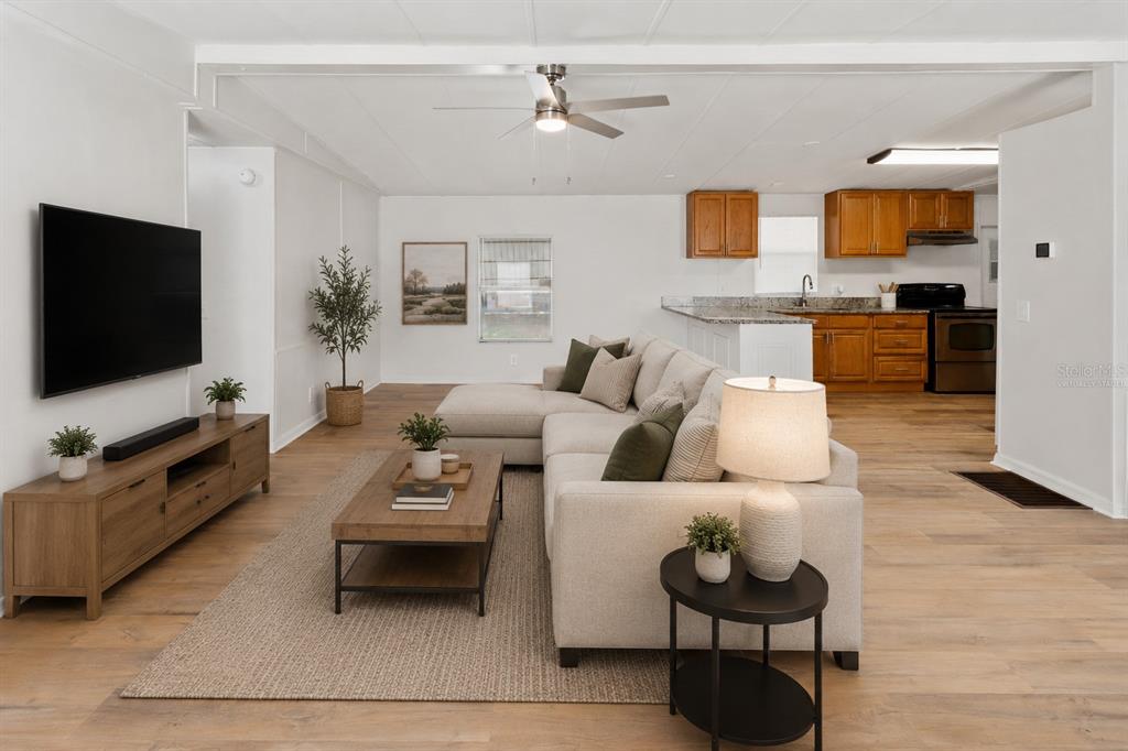 An open-concept living room and kitchen featuring light wood flooring and a sectional sofa — 6543 LURE COURT, LAKE WALES, FL
