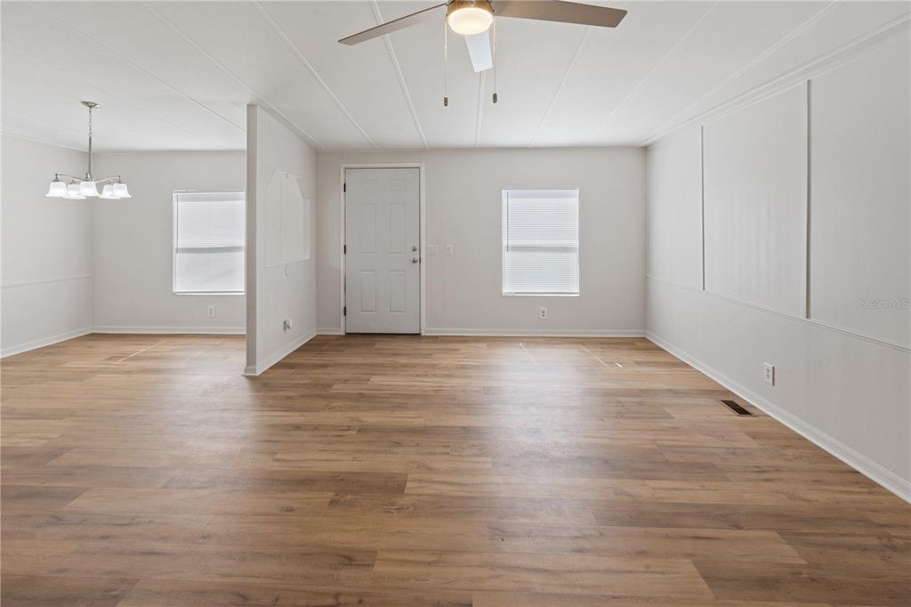 An open-concept living and dining area features light wood-look flooring and white paneled walls — 6543 LURE COURT, LAKE WALES, FL