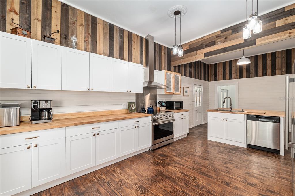 A kitchen features white cabinets, wood countertops, and vertical wood-plank wall accents — 19451 SE 2ND STREET, WILLISTON, FL