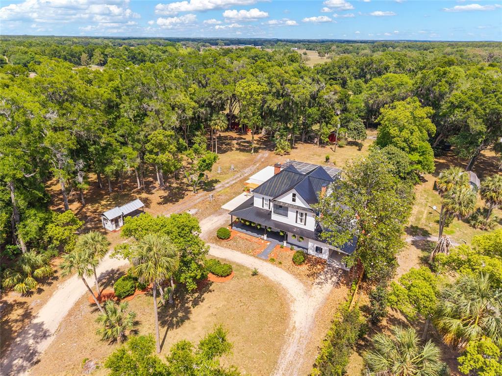 An aerial view of a white two-story farmhouse with a black metal roof and porch — 19451 SE 2ND STREET, WILLISTON, FL