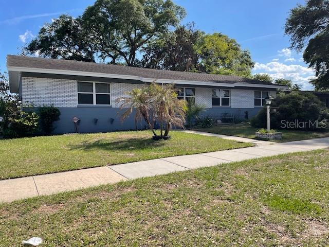 A single-story house with a white brick facade and a gray roof sits behind a lawn — 6800 ANOKA DRIVE, ORLANDO, FL