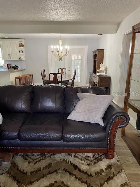 A living room with a dark leather sofa faces a dining area with a chandelier — 6800 ANOKA DRIVE, ORLANDO, FL