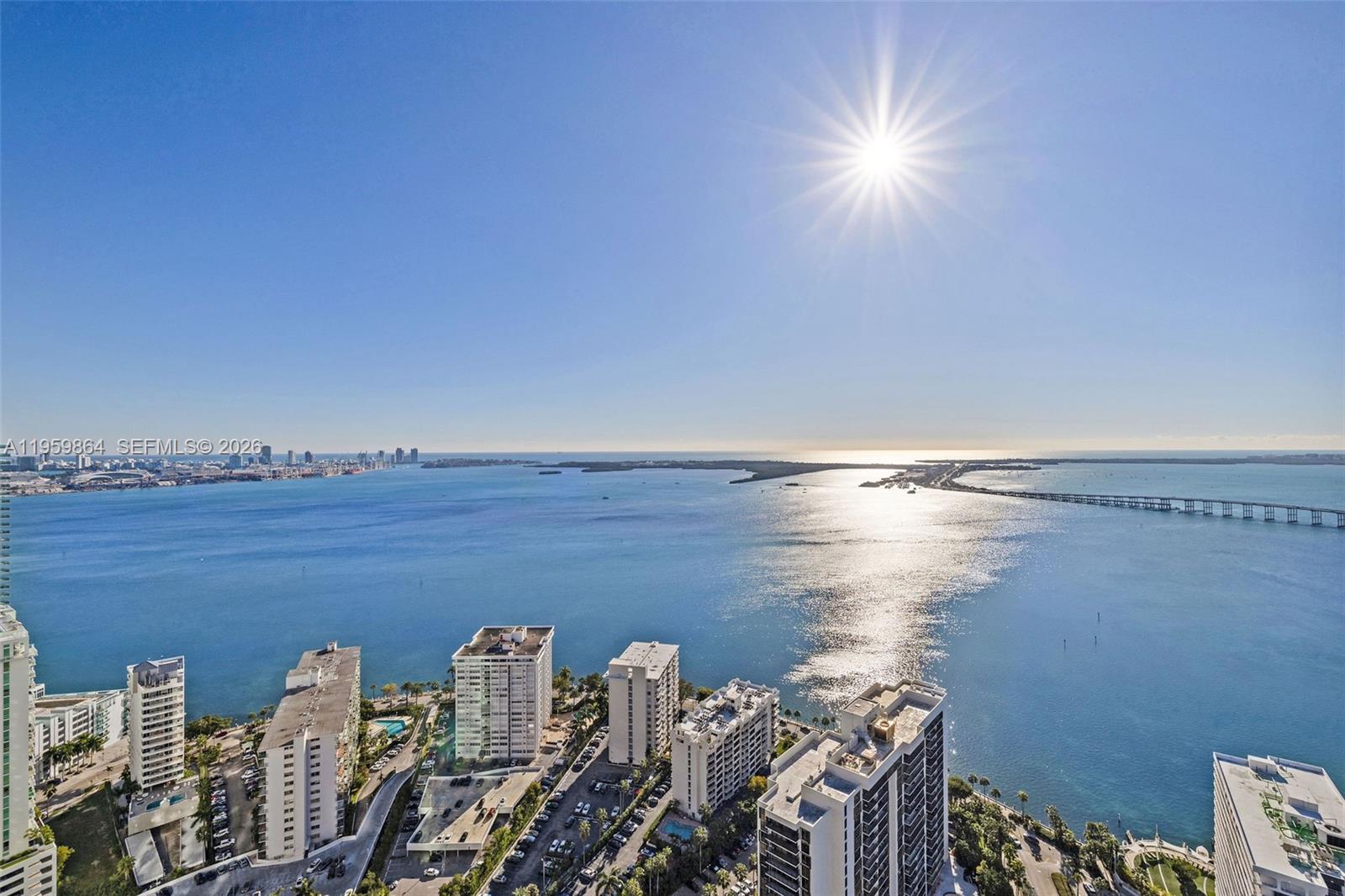 An aerial view shows a coastal city with high-rise buildings, a bridge, and the ocean — 1451 Brickell Ave # 4401, Miami FL 33131, MIAMI, FL