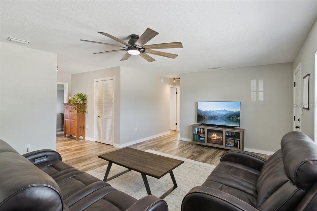 A living room with wood-look flooring, two leather sofas, a coffee table, and a ceiling fan — 220 ALDO DRIVE, BABSON PARK, FL