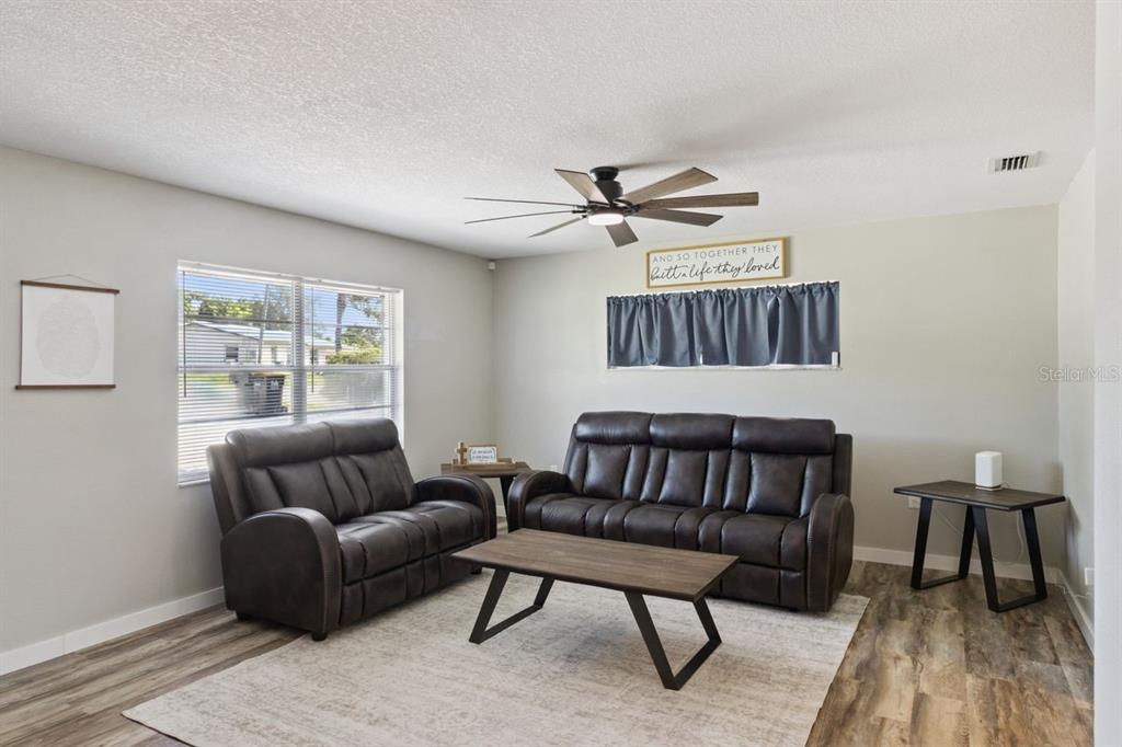 A living room features dark leather furniture, a wood coffee table, and a ceiling fan — 220 ALDO DRIVE, BABSON PARK, FL
