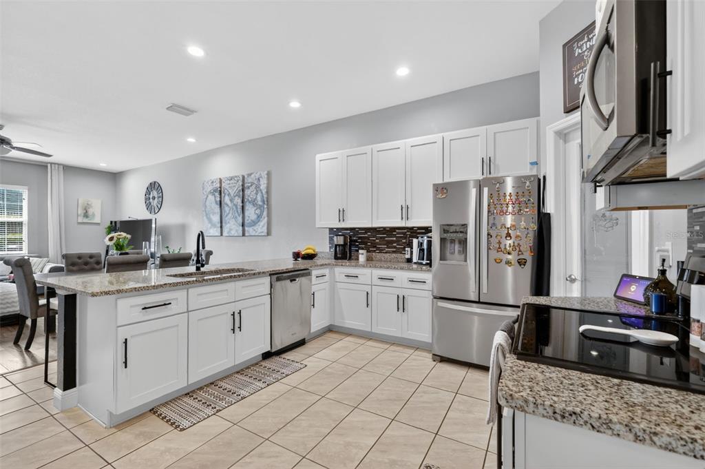 A kitchen with white cabinets, granite countertops, stainless steel appliances, and tile flooring — 1028 GREEN GATE BOULEVARD, GROVELAND, FL