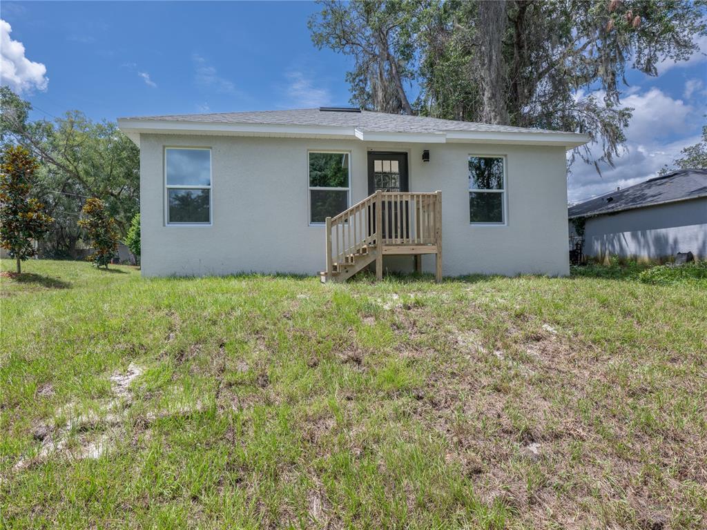 A light-colored, single-story house exterior with a wooden staircase leading to the front door — 1535 18TH STREET, ORANGE CITY, FL