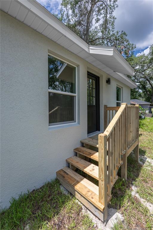 A view of a house exterior featuring a wooden staircase leading to a dark door — 1535 18TH STREET, ORANGE CITY, FL