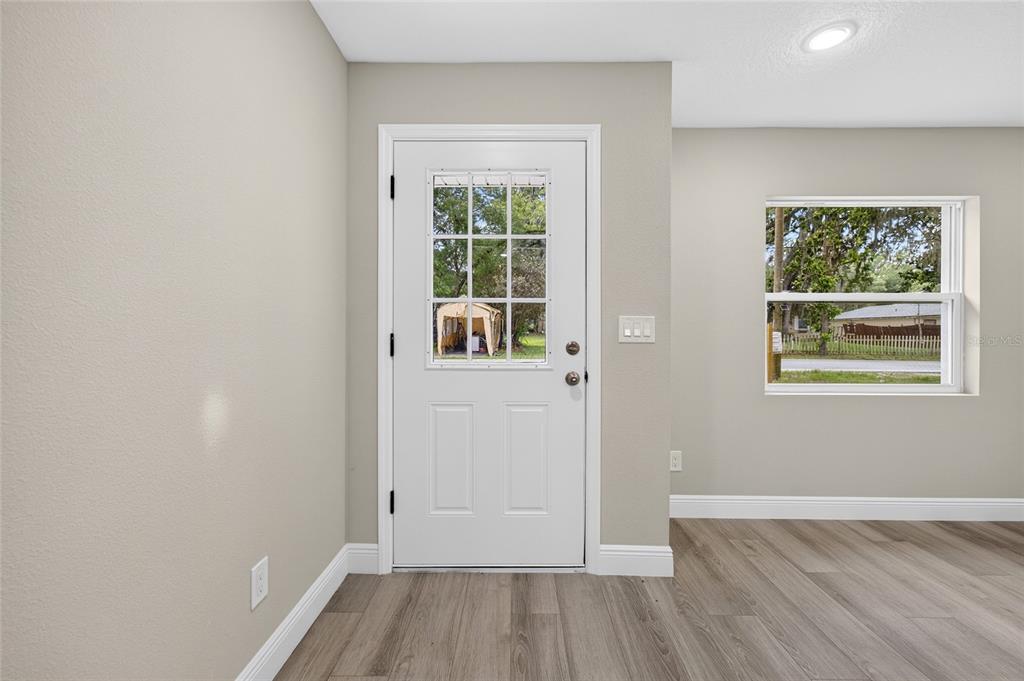An interior view of an entryway featuring a white door, gray walls, and wood-look flooring — 1535 18TH STREET, ORANGE CITY, FL