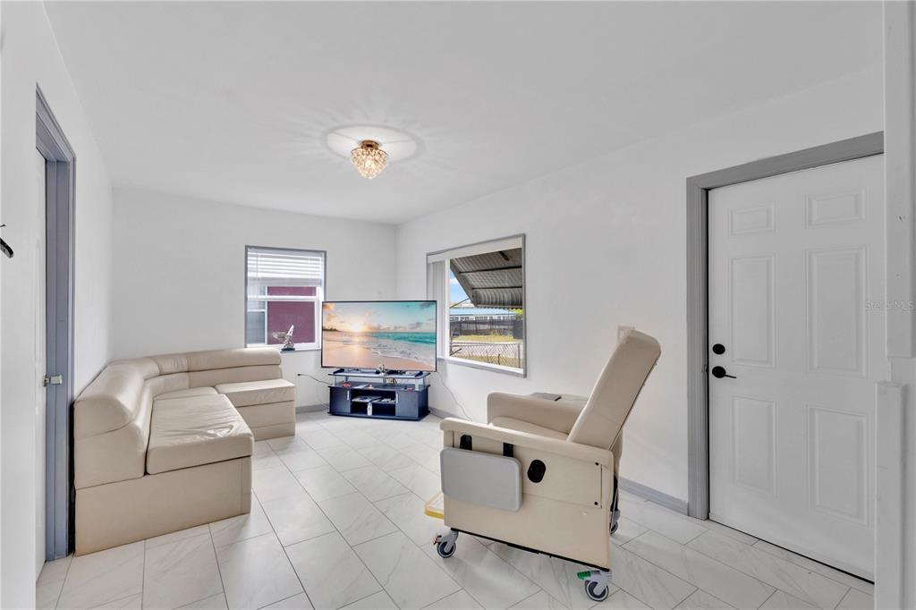 A living room features white walls, light tile flooring, a sectional sofa, and a recliner — 423 N 5TH STREET, HAINES CITY, FL