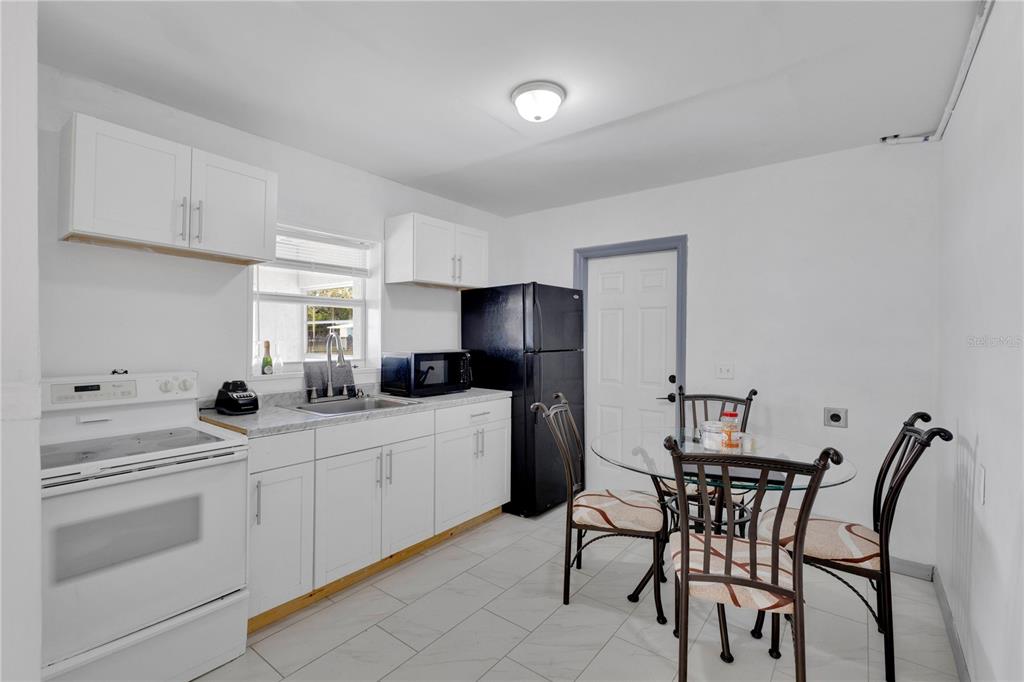 A kitchen features white cabinets, a black refrigerator, a white stove, and a dining set — 423 N 5TH STREET, HAINES CITY, FL
