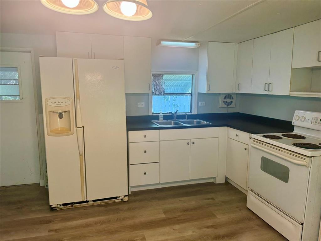 A kitchen with white cabinets, a black countertop, a white refrigerator, and a white stove — 3405 FREMONT LANE, SPRING HILL, FL