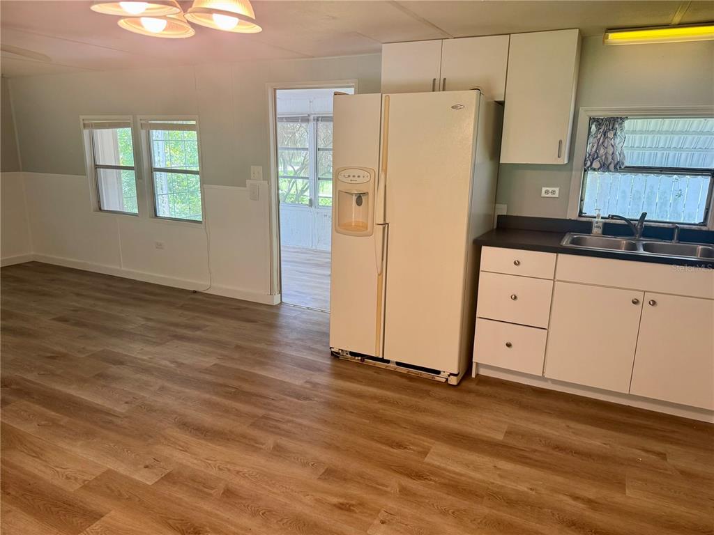 A kitchen features white cabinets, a white refrigerator, and wood-look flooring — 3405 FREMONT LANE, SPRING HILL, FL