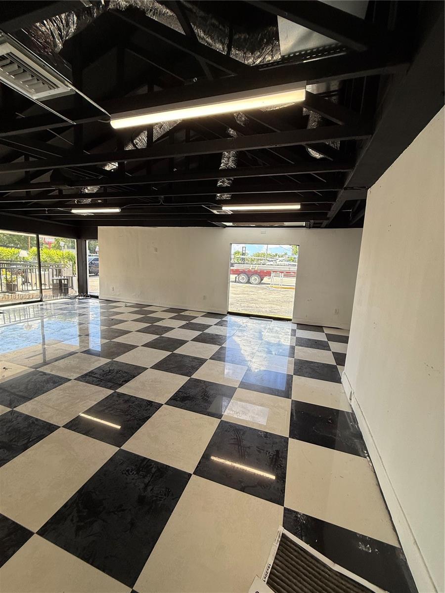 An empty commercial space features a black and white checkered floor and exposed ceiling beams — 777 NE 79th St, Miami FL 33138, MIAMI, FL